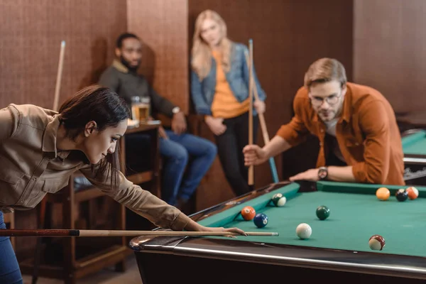 Молодые успешные многонациональные друзья играют в бильярд в баре — стоковое фото