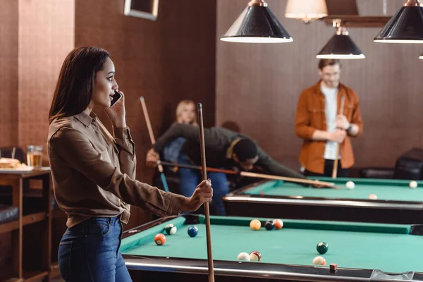 Young beautiful woman speaking on smartphone at pool bar — Stock Photo