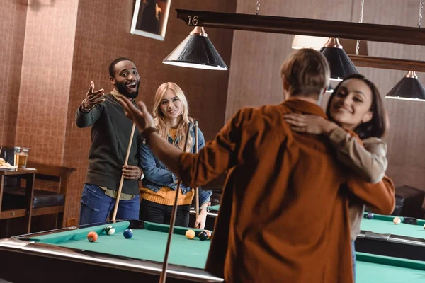 Vue arrière de jeunes amis embrassant à côté de la table de billard au bar — Photo de stock