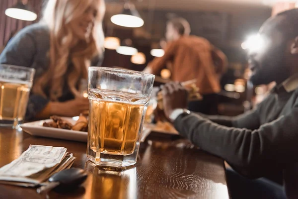 Multiethnic man and woman eating and drinking at bar — Stock Photo