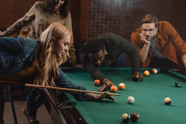 Young attractive multiethnic friends playing in pool at bar — Stock Photo