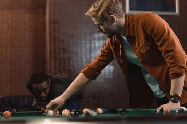 Guapos hombres multiétnicos jugando en la piscina en el bar - foto de stock
