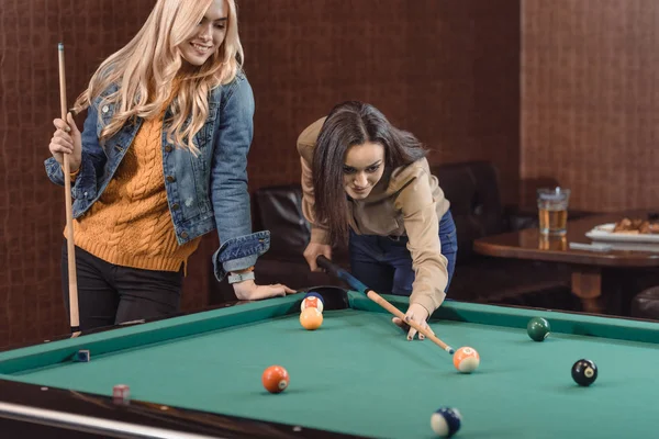 Two young girls playing in pool at bar — Stock Photo