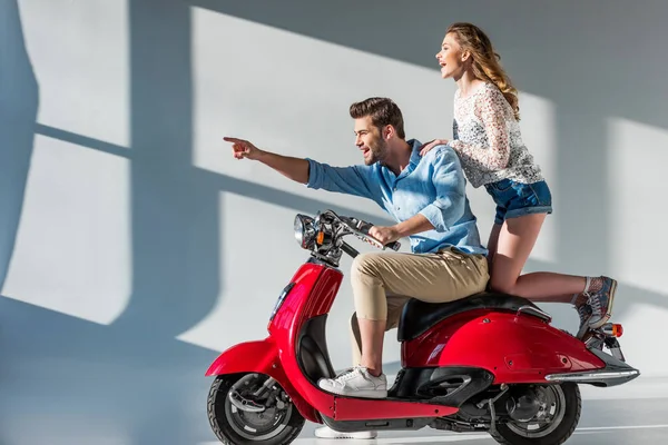 Vista laterale di uomo sorridente che punta lontano mentre seduto sullo scooter insieme con la ragazza — Foto stock