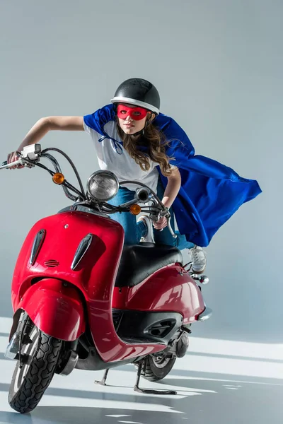 Donna in costume da supereroe e casco protettivo su scooter rosso — Foto stock