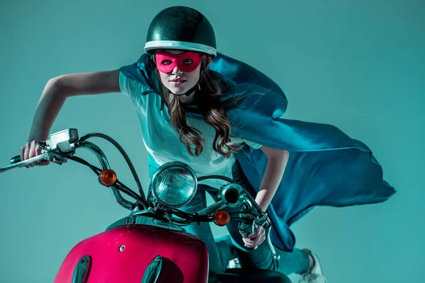 Ritratto di donna in costume da supereroe e casco protettivo cavalcando scooter rosso — Foto stock