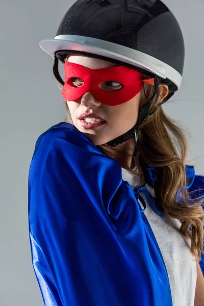 Portrait de femme réfléchie en casque, masque de super-héros et cape détournant les yeux — Photo de stock