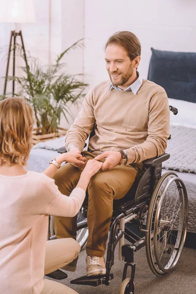 Happy husband on wheelchair and wife holding hands — Stock Photo