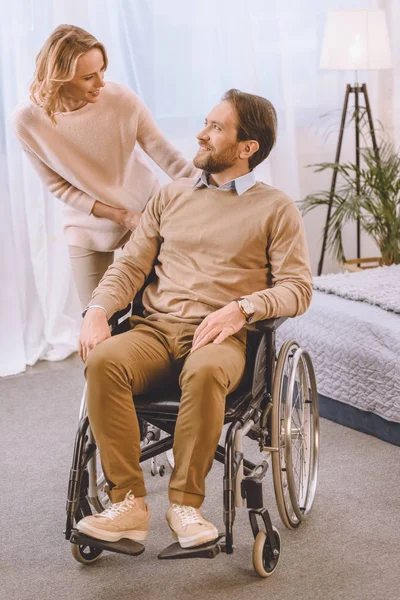 Happy husband on wheelchair and wife looking at each other — Stock Photo