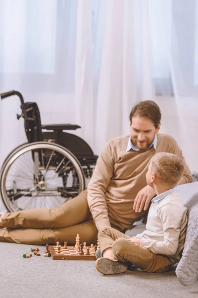 Padre con discapacidad e hijo jugando ajedrez - foto de stock