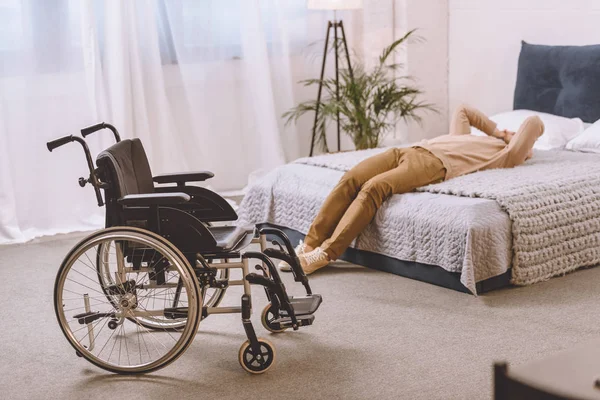 Hombre molesto con discapacidad acostado en la cama en el dormitorio - foto de stock