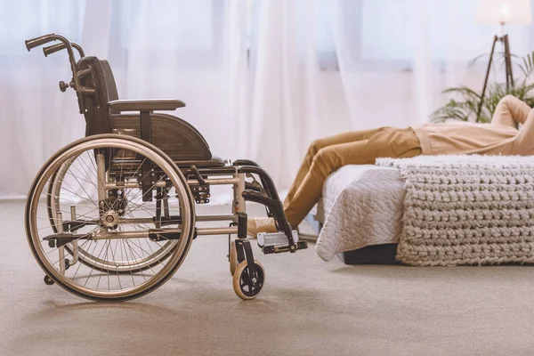 Imagen recortada de hombre con discapacidad acostado en la cama en el dormitorio - foto de stock