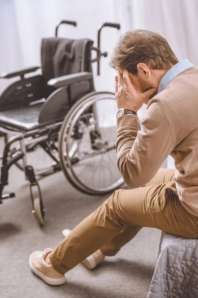 Sad man with disability sitting on bed and covering face with hand — Stock Photo