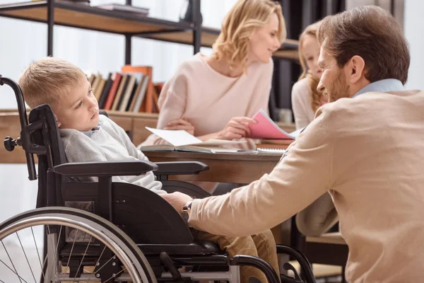 Smiling father palming son on wheelchair — Stock Photo