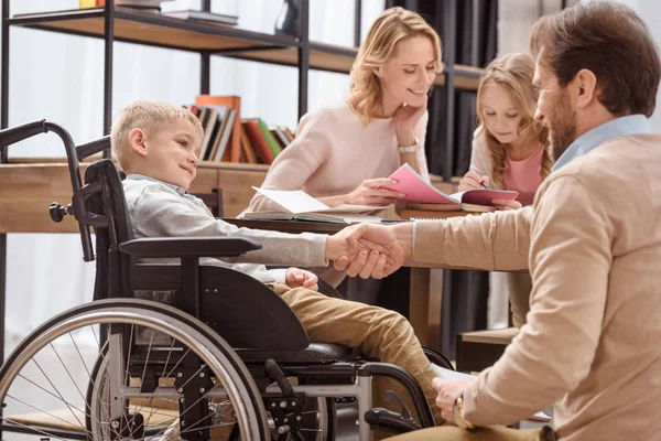 Father and son on wheelchair shaking hands — Stock Photo