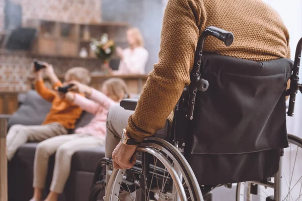 Обрізане зображення батька на інвалідному візку, дивлячись, як діти грають у відеогру — стокове фото
