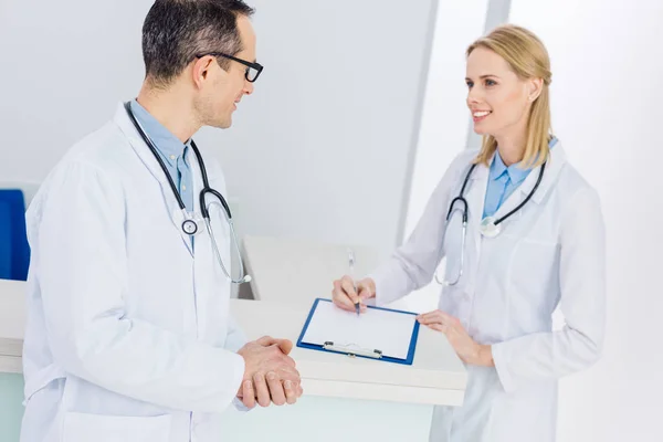 Dos médicos con batas blancas discutiendo el diagnóstico en el hospital - foto de stock