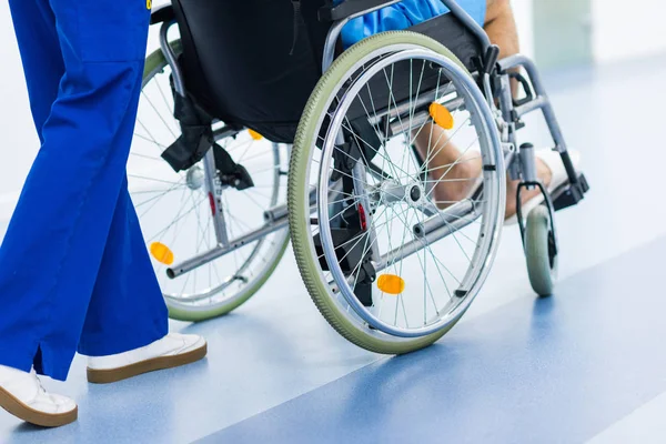 Cropped view of surgeon and patient in wheelchair in hospital corridor — Stock Photo
