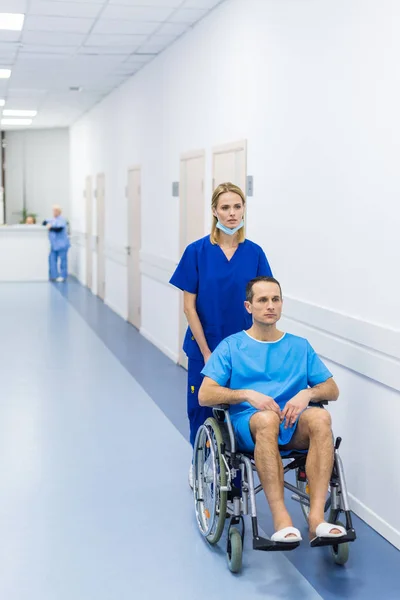 Хирург и пациент в инвалидной коляске в больничном коридоре — стоковое фото