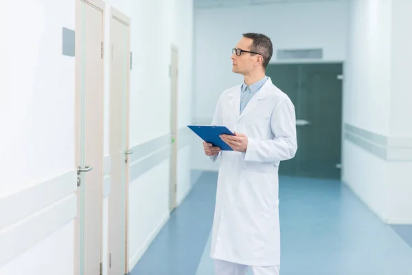 Male doctor in white coat holding diagnosis in hospital — Stock Photo