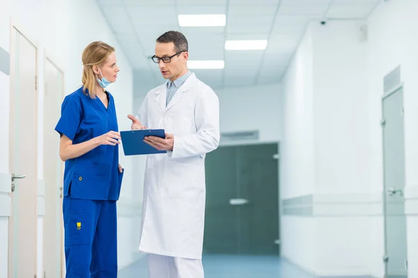 Лікар у білому пальто та жіночий хірург обговорюють діагностику в лікарні — стокове фото