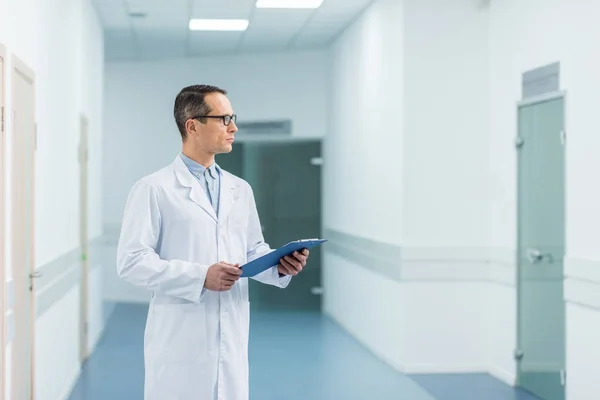 Male doctor in white coat holding diagnosis in hospital — Stock Photo