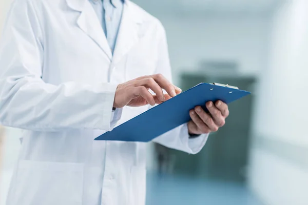 Cropped view of doctor in white coat holding diagnosis in hospital — Stock Photo