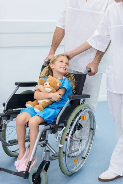 Abgeschnittenes Bild von Ärzten, die lächelndes Kind im Rollstuhl bewegen — Stockfoto