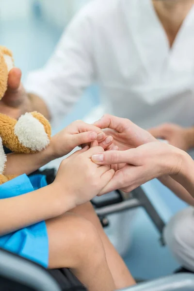 Cropped image of doctor and patient holding hands — Stock Photo