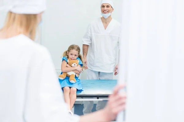 Médicos que preparan al niño asustado para la cirugía en quirófano - foto de stock