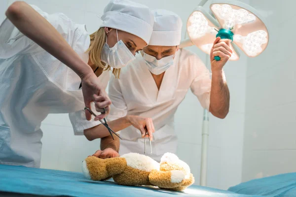 Médicos femeninos y masculinos que hacen la cirugía para el juguete suave - foto de stock