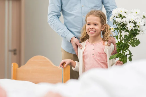 Imagen recortada de feliz hija y padre sosteniendo ramo de flores y mirando hacia otro lado - foto de stock
