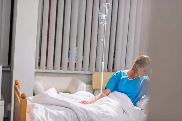 Больная женщина закрывает лицо рукой на больничной койке — стоковое фото