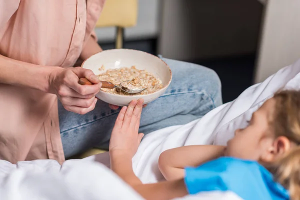 Immagine ritagliata del bambino malato che rifiuta il cibo dalla madre — Foto stock