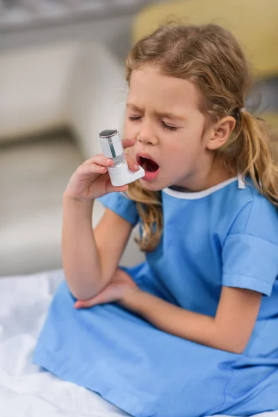 Niño enfermo que usa inhalador de asma con los ojos cerrados - foto de stock