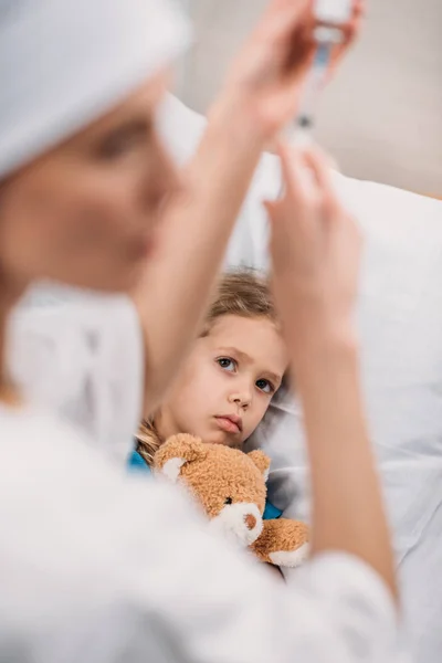Female doctor preparing vaccination for ill scared kid — Stock Photo