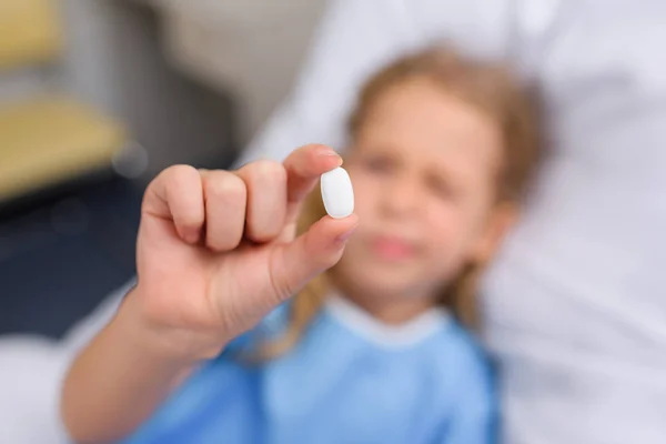 Vue aérienne de l'enfant tenant et regardant pilule — Photo de stock