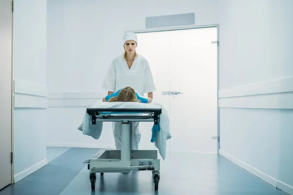 Enfermeira paciente pré-escolar em movimento na maca médica no corredor — Stock Photo