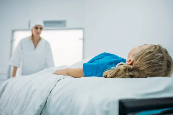 Femme médecin déplacement préscolaire patient sur civière médicale dans le couloir — Photo de stock