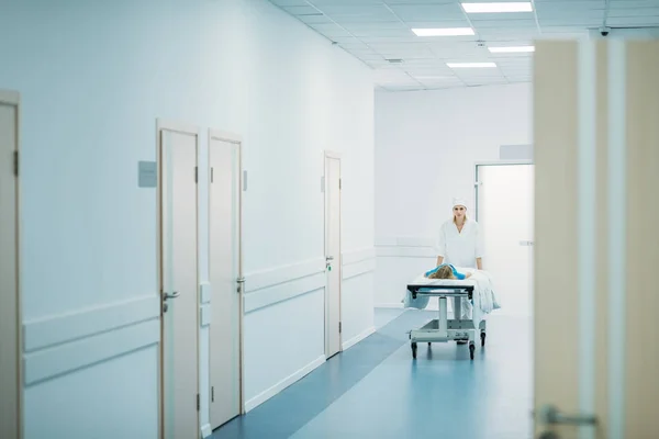 Doctor moving preschooler patient on medical stretcher in corridor — Stock Photo