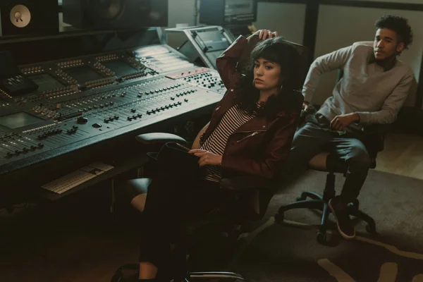 Jóvenes músicos deprimidos sentados en sillas en un estudio de grabación - foto de stock