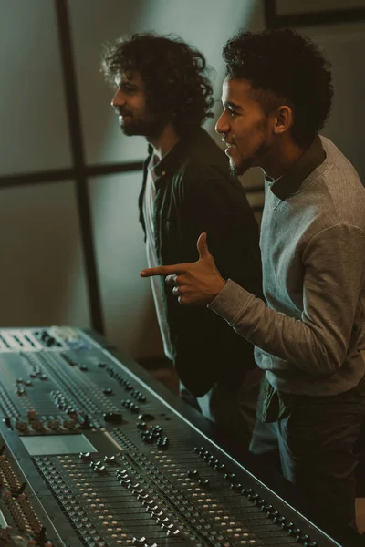 Sorrindo jovens produtores de som no estúdio de gravação — Fotografia de Stock