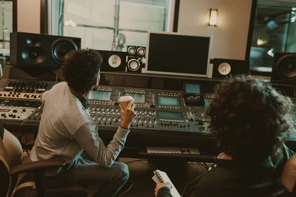 Back view of sound producers looking at blank monitor at recording studio — Stock Photo