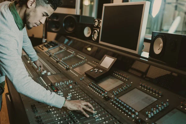 Productor de sonido afroamericano concentrado trabajando con ecualizador gráfico - foto de stock