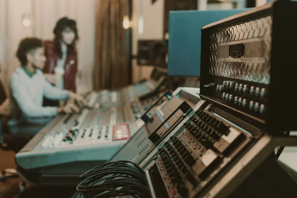 Plan rapproché d'amplificateurs sonores dans un studio d'enregistrement avec des producteurs flous derrière — Photo de stock