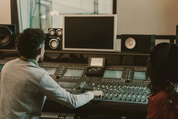 Productores de sonido mirando el monitor en blanco en el estudio de grabación - foto de stock