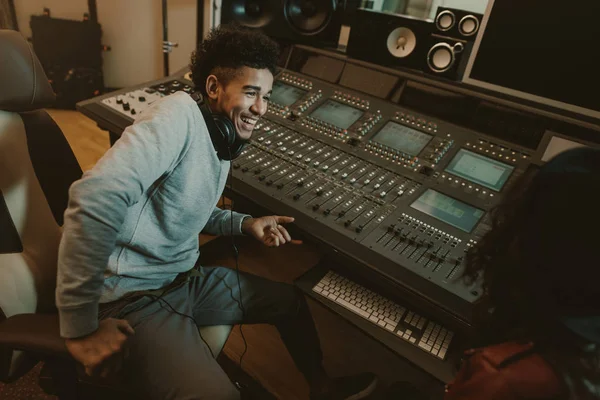 Feliz joven productor de sonido sentado en el estudio - foto de stock