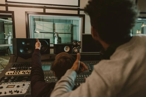 Productores de sonido mostrando pulgares hasta cantante en el estudio de grabación - foto de stock