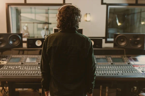 Vue arrière du producteur sonore dans les écouteurs au studio — Photo de stock