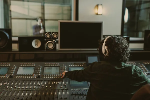 Vue arrière du producteur sonore travaillant en studio tout en enregistrant la chanson — Photo de stock